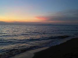 Sunset sky and palm leaves on beach background photo