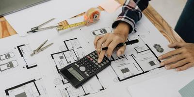 arquitectos conceptuales, ingeniero sosteniendo un bolígrafo que señala arquitectos de equipos en el escritorio con un plano en la oficina. foto
