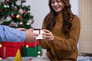 Happy woman giving Christmas and New Year Gift box to woman at Home.Family Xmas celebration. Christmas decoration. Relationship photo