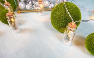 magic garland - Toy Christmas trees in glass jars and green grass balls, on a blue background. a glass casket with silver ornaments. photo