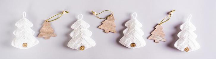 Knitted and wooden fir trees in a row on a gray background. Web banner photo