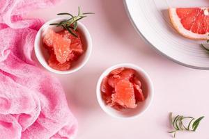 Peeled pieces of grapefruit and rosemary in a bowl on the table. Cocktail ingredients. Top view photo