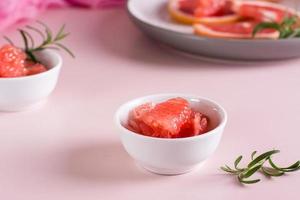 Peeled pieces of grapefruit and rosemary in a bowl on the table. Cocktail ingredients. photo