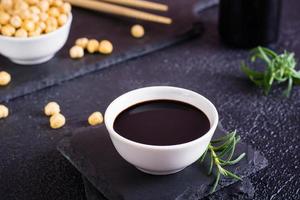 Soy sauce in a bowl and soy beans on the table. photo