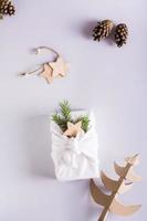 Furoshik with spruce branches, cones and a cardboard spruce on a light background. Vertical view photo