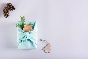 Furoshik with fir branches, wooden decorations and pine cones on a light paper. Eco-Friendly Gifts photo