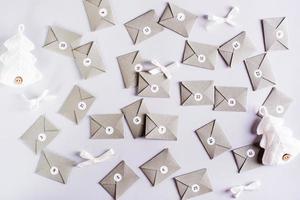 Envelopes for the advent calendar are laid out randomly and knitted fir trees on a gray background photo