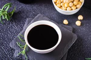 Bowl with soy sauce, rosemary and soy beans on the table. photo