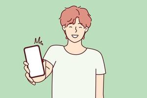 Happy man showing smartphone screen and smiling to recommend cool applications. Positive college age guy holding mobile phone with blank display boasts website. Flat vector illustration