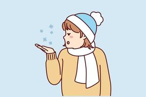 Little teen girl stretches out palm to pick up snowflakes standing outdoors in cold weather. Child in hat and scarf enjoys winter holidays and looks with surprise at falling snow. Flat vector image