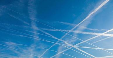 Image of several contrails caused by airplanes in a blue sky photo