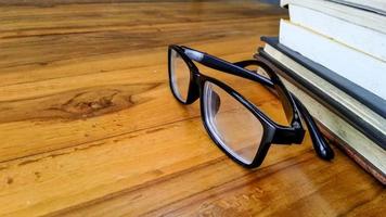 glasses and books on a wooden table with copy space photo