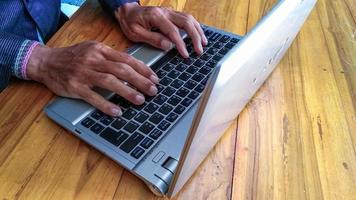 businessman hand working with laptop on wooden table photo