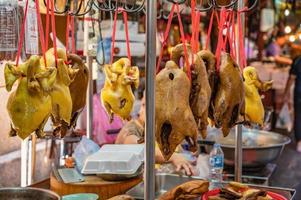 pollo hervido y pato al vapor colgando en el puesto del mercado en el antiguo callejón del centro del mercado de yaowarat chinatown bangkok city tailandia. foto