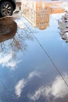 car and puddle from melting snow in city in spring photo