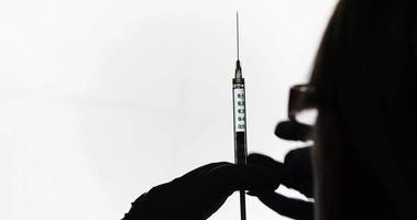 4k Arzt oder Krankenschwester mit Impfstofffläschchen und Nadelspritze silhouettiert