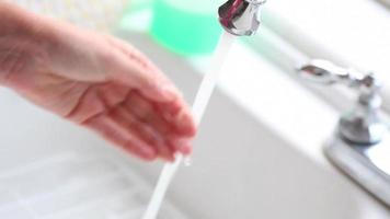 Washing hands with soap and water in white sink, close up video