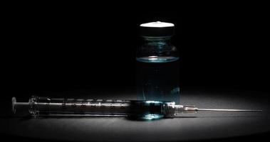 Rotating view of coronavirus vaccine and syringe on dark background video