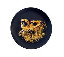 Top view of Blueberry crumble on black dish or plate isolated on white background with clipping path and make selection. Flat lay of dessert. Food handmade with fruit and crackers topping. Sweet food. photo