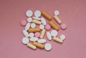 montón de pastillas sobre fondo rosa. foto