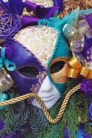 colorido carnaval veneciano dorado y morado y máscara de fiesta con plumas y cintas en arreglo de invierno con ramas de abeto. imagen vertical foto