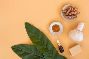 Top view of herbal compress ball with Thai herbal, turmeric, essential oil and bar soap on orange pastel background. Spa background conce photo