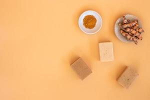 Top view of turmeric and bar soap on orange pastel background. Spa background concept. photo
