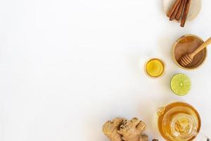 Top view of a cup of tea with ginger root, lime, cinnamon and teapot on white background. Health drink concept photo