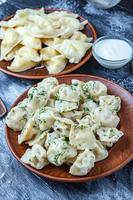 Traditional russian pelmeni or ravioli, dumplings with meat on wood black background. Russian food and russian kitchen concept. photo