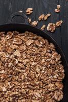 Walnut background. Peeled walnuts on a iron plate on black. walnuts a real super food full of vitamins and vegetable fats photo