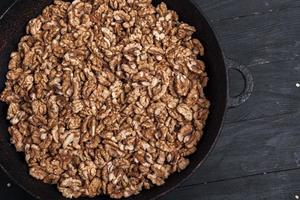 Walnut background. Peeled walnuts on a iron plate on black. walnuts a real super food full of vitamins and vegetable fats photo