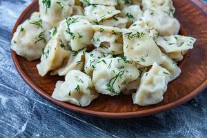 Traditional russian pelmeni or ravioli, dumplings with meat on wood black background. Russian food and russian kitchen concept. photo