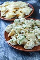 Traditional russian pelmeni or ravioli, dumplings with meat on wood black background. Russian food and russian kitchen concept. photo