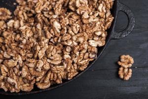 Walnut background. Peeled walnuts on a iron plate on black. walnuts a real super food full of vitamins and vegetable fats photo