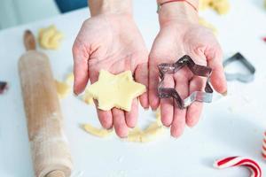 familia cocinando pasteles caseros. manos de mamás y niños sosteniendo cortadores de galletas. cocina familiar endecha plana. dulce hogar. concepto de felicidad. foto