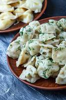 pelmeni o raviolis rusos tradicionales, albóndigas con carne sobre fondo negro de madera. comida rusa y concepto de cocina rusa. foto