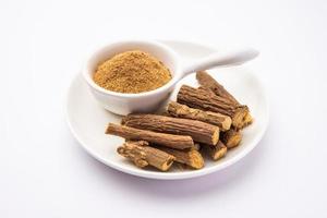 Ayurvedic Mulethi or Liquorice root stick or jeshthamadh powder served in a bowl over moody background photo