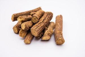 Ayurvedic Mulethi or Liquorice root stick or jeshthamadh powder served in a bowl over moody background photo