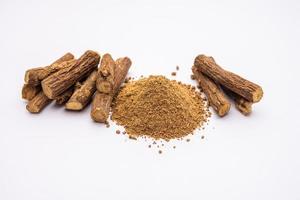 Ayurvedic Mulethi or Liquorice root stick or jeshthamadh powder served in a bowl over moody background photo