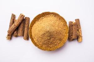 Ayurvedic Mulethi or Liquorice root stick or jeshthamadh powder served in a bowl over moody background photo