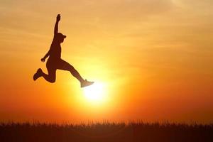 Silhouette. Man jumping happily in the meadow. photo