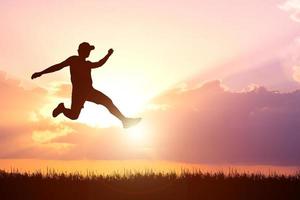 Silhouette. Man jumping happily in the meadow. photo