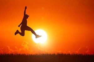 Silhouette. Man jumping happily in the meadow. photo