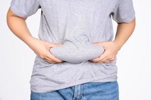 Asian fat women has overweight in jeans. woman's hand holding excessive belly fat isolated on white background. concept of surgery and subcutaneous fat breakdown. photo