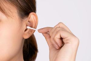 mujer limpiándose la oreja con un hisopo de algodón. una mujer sufrió una infección después de usar los palos incorrectamente. foto