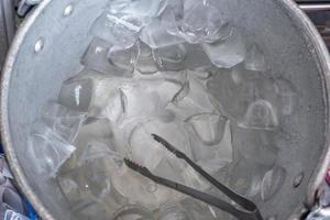 hielo en un balde plateado con pinzas para hielo. foto