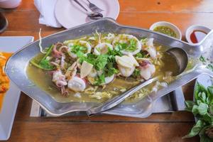 Steamed squid with lime Thai food, set in a stainless fish-shaped hot pot. photo