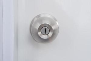 Close-up of a silver doorknob mounted on a white door. photo