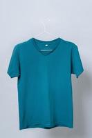Worn blue t-shirt hanging on a hanger against gray background photo