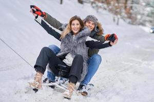 pareja divirtiéndose con trineo en la nieve en invierno foto